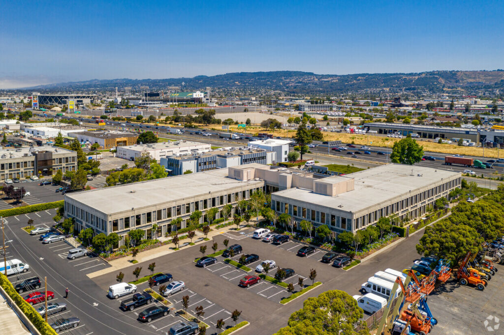 Aerial view of the Oakport Building and parking lot. The Santa Cruz Mountains are visible across the bay.