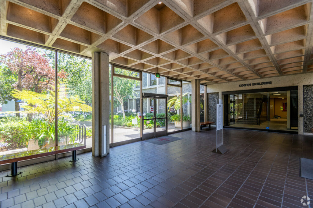 Entryway of 7901 Oakport. Tiled floors, decorative ceilings, and benches look out floor-to-ceiling windows.