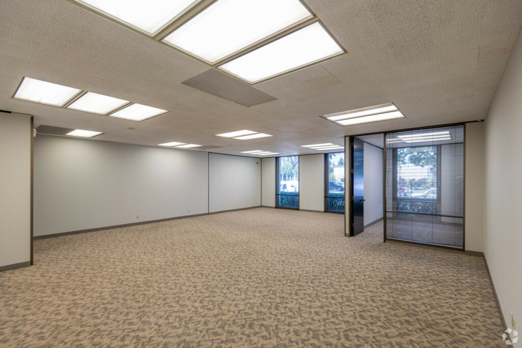 Open Bullpen area in Suite. Private corner office and two floor-to-ceiling windows line the back wall.