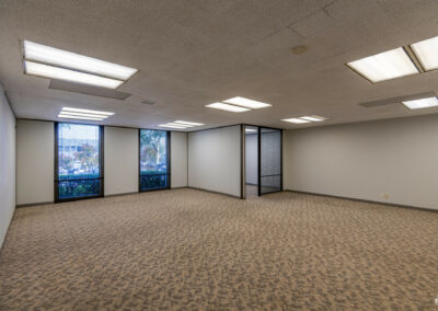 Open Bullpen area in Suite. Private corner office and two floor-to-ceiling windows line the back wall.