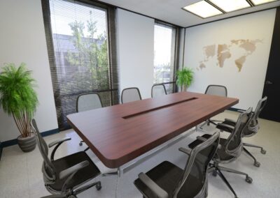 Virtually staged conference room in Suite. Two floor-to-ceiling windows look out on trees and other buildings.