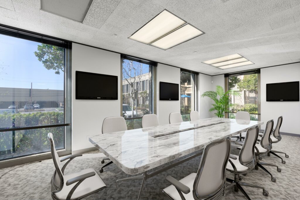 Large conference room in suite. Long marble desk, surrounded by 10 chairs and mounted TVs. 4 wall-height windows.