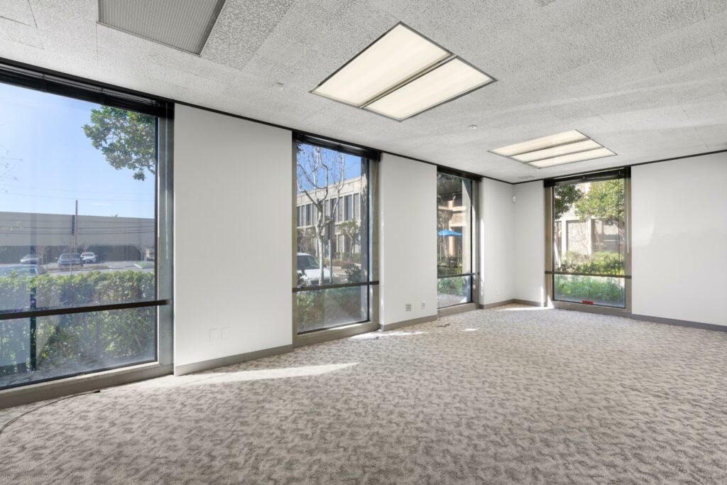 Large conference room in Suite. Four floor-to-ceiling windows face trees and other office buildings.