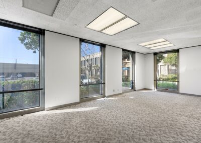 Large conference room in Suite. Four floor-to-ceiling windows face trees and other office buildings.