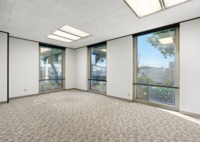 Conference room in Suite. Three floor-to-ceiling windows face trees and other office buildings.