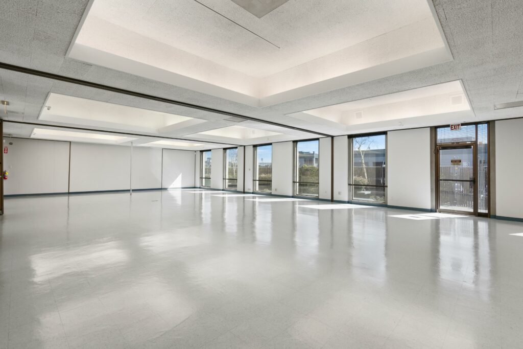 A virtually staged photo of the main open space of Suite #1000. Six floor-to-ceiling windows line the right wall.