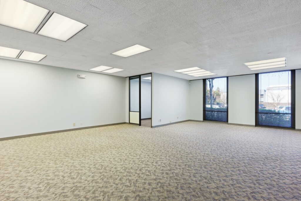 Open Bullpen area in Suite. Private corner office and two floor-to-ceiling windows line the back wall.