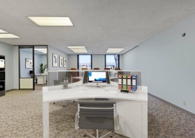 Virtually staged cubicles in a bullpen layout, Suite. Glass-walled private corner office, floor-to-ceiling windows in background.